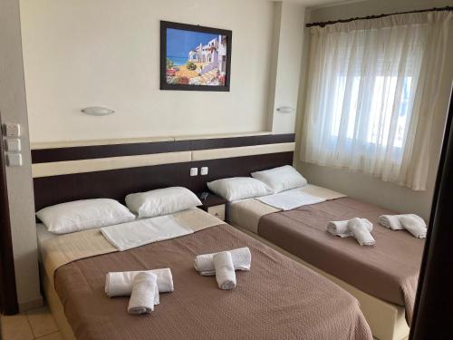 ein Zimmer mit 3 Betten und Handtüchern darauf in der Unterkunft VILLA HARIKLIA in Paralia Katerinis
