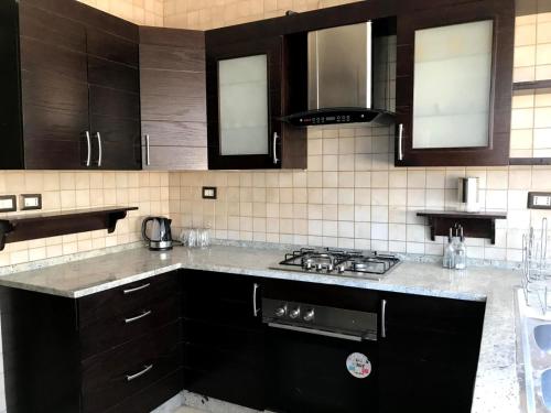 eine Küche mit schwarzen Schränken und einem Herd mit Backofen in der Unterkunft MK6 - Two bedroom Apartment in Amman