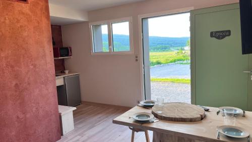 a kitchen with a table and a large window at Hôtel En Tilleul in Pont-du-Navoy