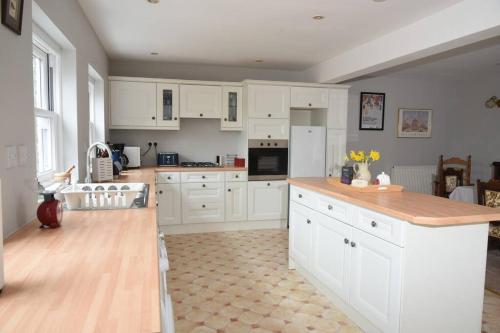 a kitchen with white cabinets and a counter top at Cotswold dog-friendly holiday home in Stroud