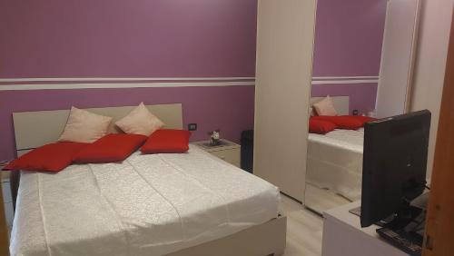 1 dormitorio con cama con almohadas rojas y espejo en Appartamento Amy, en Perugia