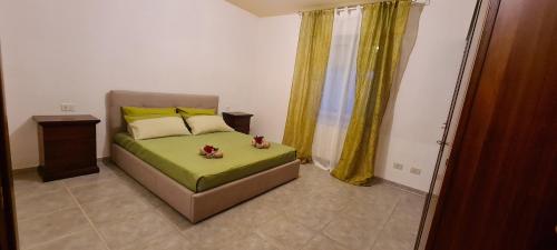 sypialnia z łóżkiem z zieloną pościelą i żółtymi zasłonami w obiekcie Kolbe's house w mieście Siniscola