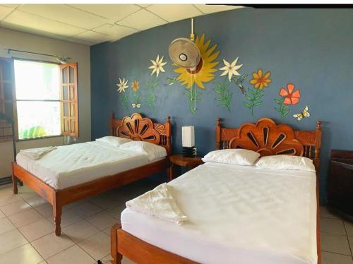 2 camas en una habitación con flores pintadas en la pared en El Mirador Ecológico, Ometepe, en Altagracia