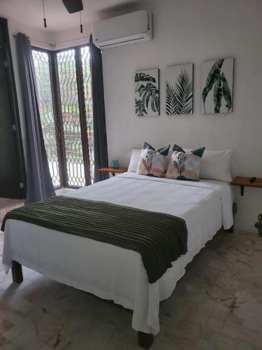 a bedroom with a large white bed and a window at Casa Las Palmas in Cancún