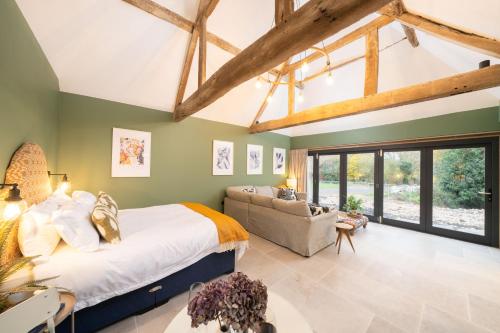 um quarto com uma cama grande e um sofá em Spinney - a unique open plan barn, with private garden em Evesham