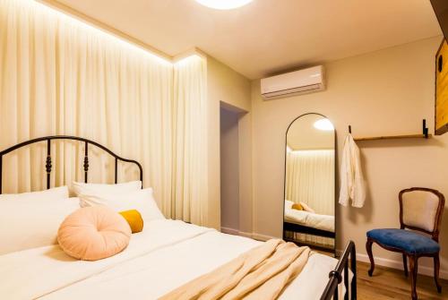 a bedroom with a bed and a chair and a mirror at jabotinsky 37 in Zikhron Ya‘aqov