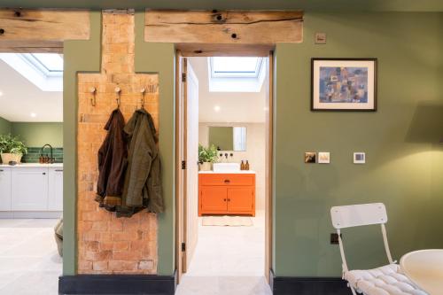 a bathroom with green walls and a brick wall at Spinney - a unique open plan barn, with private garden in Evesham