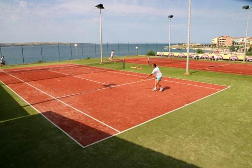 a man is playing tennis on a tennis court at SMARAGD on the beach in Povljana