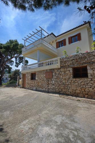 a house with a balcony on top of a stone wall at Eleni's Guest House in Patitiri