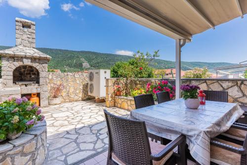 a patio with a table and a stone fireplace at Apartman Bruna in Cres