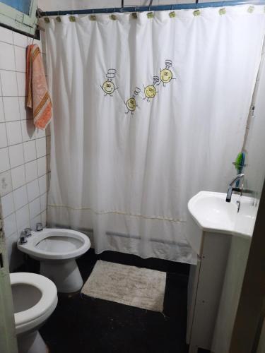 e bagno con tenda per la doccia, servizi igienici e lavandino. di Kela a Buenos Aires