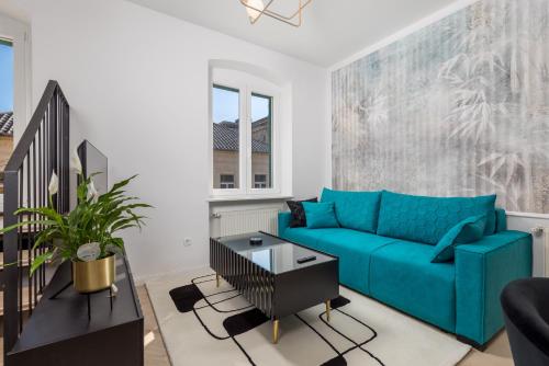 a living room with a blue couch and a table at Apartments Madeleine in Rijeka