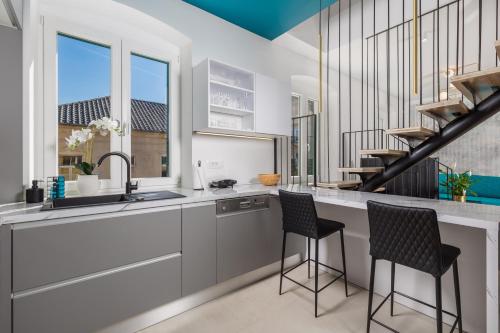 a kitchen with a sink and two bar stools at Apartments Madeleine in Rijeka