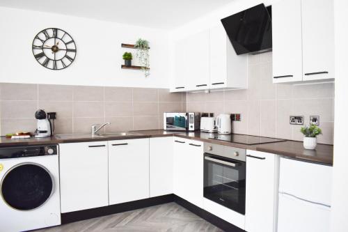 cocina blanca con armarios blancos y lavavajillas en City Center Apartments FREE PARKING en Liverpool