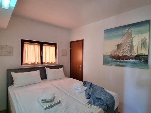 a bedroom with a bed with a sailboat painting on the wall at Orkula Hidden Paradise- Robinson Holiday House in Banj