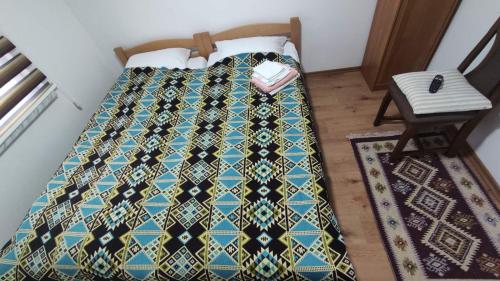 a bed with a quilt on it next to a chair at Glossy private apartment in Sarajevo