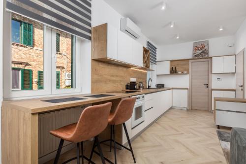 a kitchen with white cabinets and a counter with stools at Apartments Madeleine in Rijeka