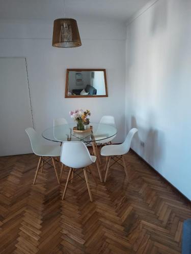 a dining room with a glass table and white chairs at Moderno Depto Pleno Centro in Rosario