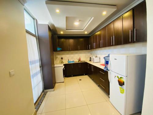 a kitchen with wooden cabinets and a white refrigerator at IZA Serene city centre apartments in Kigali