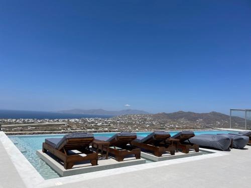 a pool with chaise lounge chairs and a swimming pool at Sunset Hill Suites in Mýkonos City