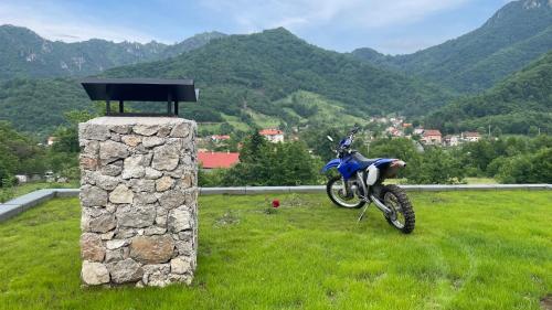 a motorcycle parked in a field with mountains in the background at Josanica Bed&Breakfast in Konjic