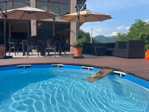 a blue swimming pool with a table and umbrella at Josanica Bed&Breakfast in Konjic