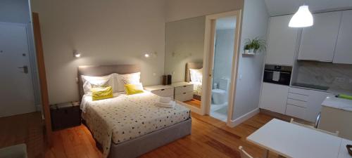 a bedroom with a bed with yellow pillows and a kitchen at S Bento Boutique Apartment in Porto