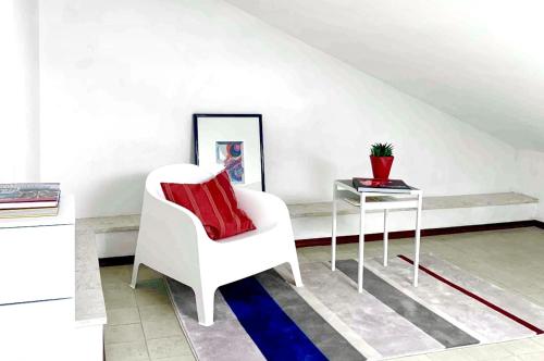 a living room with a white chair and a table at APPARTAMENTO SFERISTERIO in Macerata