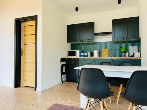 a kitchen with green cabinets and a table and chairs at Apartament Na Szlaku 