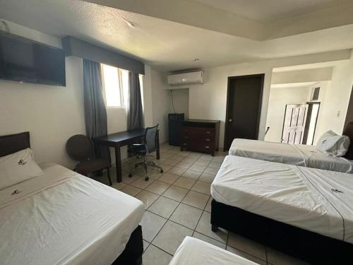 a hotel room with two beds and a desk at Hotel Don Quijote in Mexicali