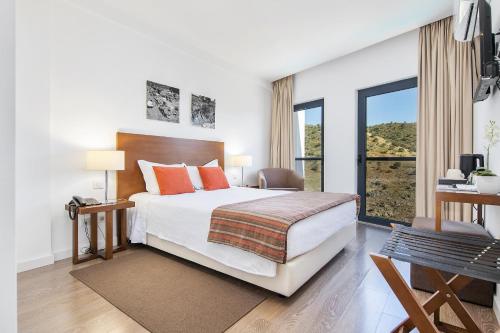 a bedroom with a bed and a large window at Hotel Museu in Mértola