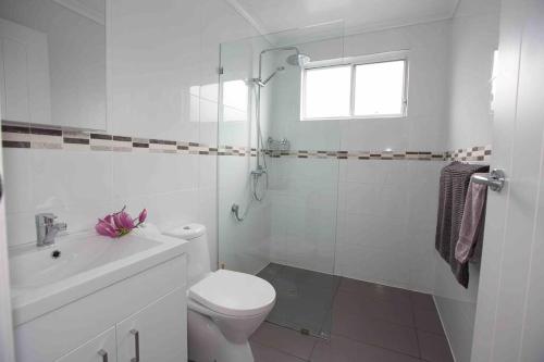 a white bathroom with a toilet and a shower at Magnolia Cottage in Coffs Harbour