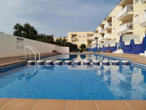 una piscina con sillas y un edificio en Apartamento HOUSE FRANMAR en Sant Jaume d'Enveja
