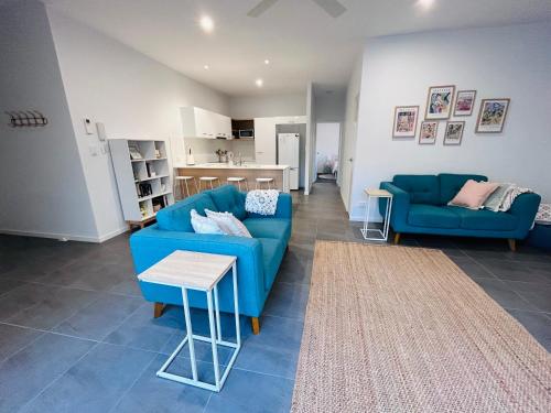 sala de estar con 2 sofás azules y cocina en Unit 1 - Manly Boutique Apartments en Brisbane