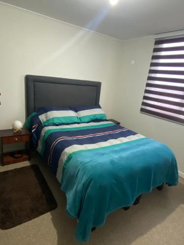 a bedroom with a bed with blue sheets and a window at Dpto Full Equipado ,6 Pers ,2 Baños + Estacionamiento in Puerto Montt