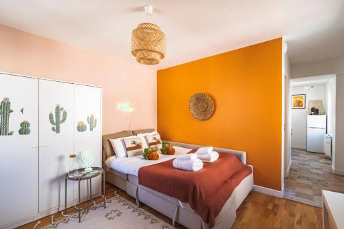 1 dormitorio con 1 cama con pared de color naranja en ExploreReims - California Dream studio proche gare/centre en Reims