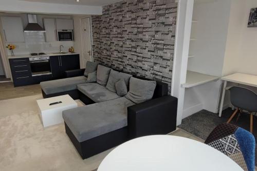 a living room with a couch and a brick wall at Cosy 1 Bedroom Flat in Southam in Southam