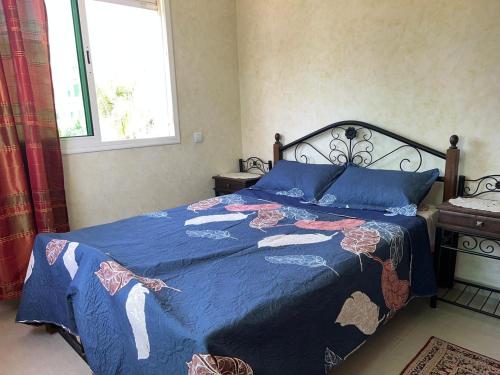 ein Schlafzimmer mit einem Bett mit blauer Decke und einem Fenster in der Unterkunft Perle sur la mer in Mohammedia