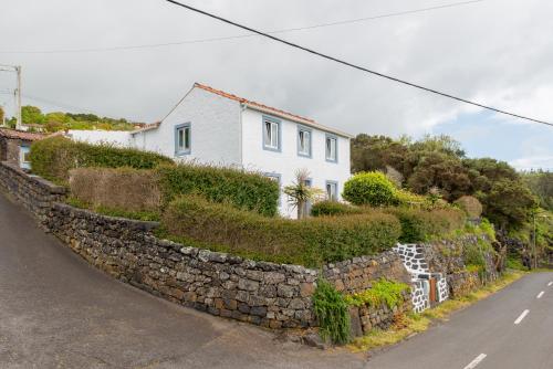 eine steinerne Mauer mit einem Haus auf einer Straße in der Unterkunft Lobo do Mar in Calheta de Nesquim