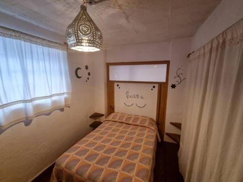 a small bedroom with a bed and a chandelier at En el Corazón de Valle, Casa Luz María. in Valle de Bravo