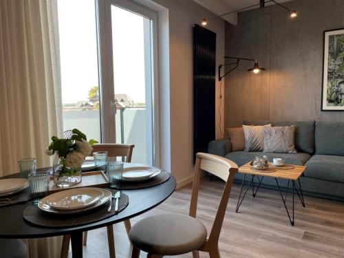 een woonkamer met een tafel en een bank bij Stylowy Apartament - Port Mielno in Mielno
