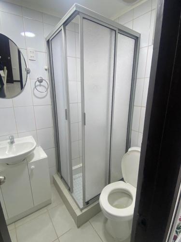 uma casa de banho com um chuveiro, um WC e um lavatório. em Hostal Florecer em Angol