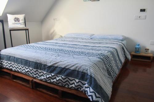 a bedroom with a bed with a blue and white blanket at Gijon Surf Hostel in Gijón