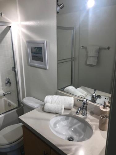 a bathroom with a sink and a toilet and a mirror at The Palomino - Modern, Stylish, Secure Entry, Spacious Condo with 2 Master Bedrooms, WLK to Pier in Los Angeles