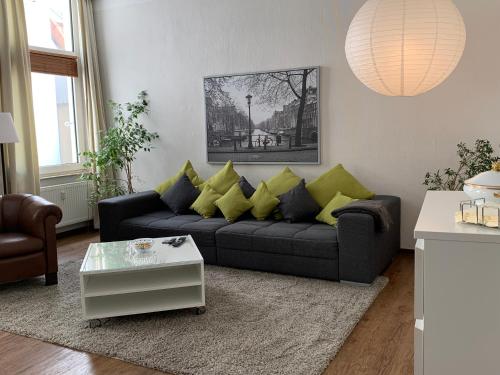 a living room with a black couch with yellow pillows at TOP-Zentrum Fußgängerzone, 82 qm, Küche, Parkplatz in Oldenburg
