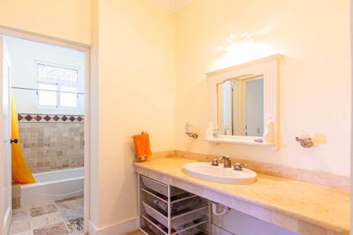 a bathroom with a sink and a mirror and a tub at Victorian Condominium, Cabarete! in Cabarete
