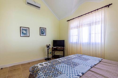 Schlafzimmer mit einem Bett, einem TV und einem Fenster in der Unterkunft Victorian Beach Front, Cabarete in Cabarete