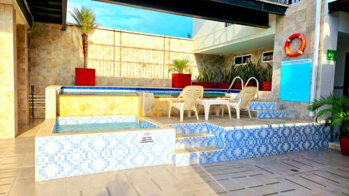 patio ze stołem i krzesłami przy basenie w obiekcie Hotel Carolina Del Mar w mieście Santa Marta