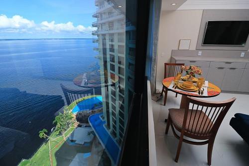 a room with a table and a view of the water at Tropical Executive 1307 With View in Manaus