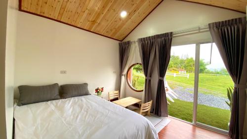 ein Schlafzimmer mit einem Bett und einem großen Fenster in der Unterkunft ไร่วิวทิวเขา ลานกางเต็นท์ ฟาร์มสเตย์ in Ban Nong Tum